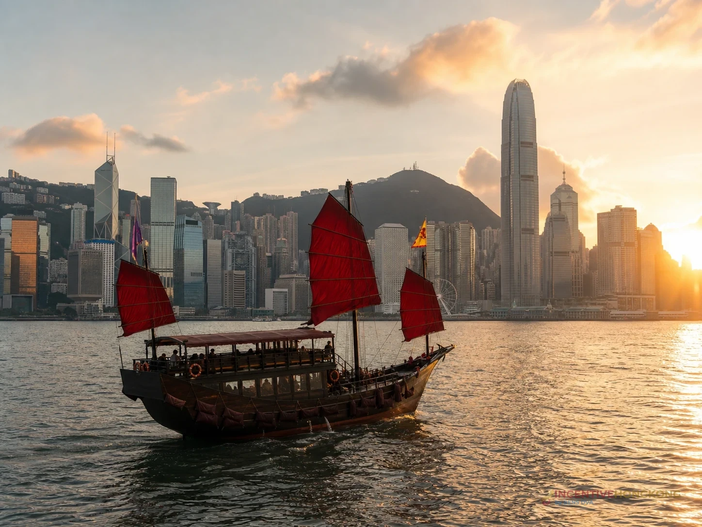 เรือใบแดงล่องในอ่าววิคตอเรียท่ามกลางเส้นขอบฟ้าฮ่องกงยามค่ำ